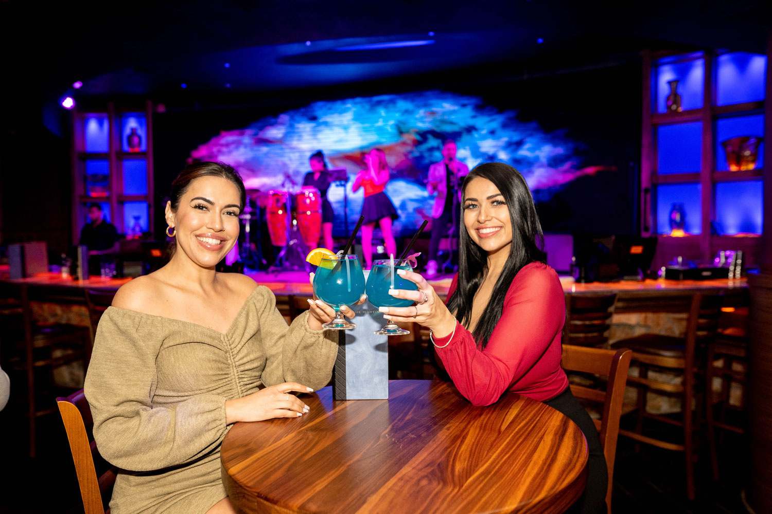 Two women toasting with Blue Martinis in an upscale lounge, capturing the vibrant nightlife and signature blue martini experience.