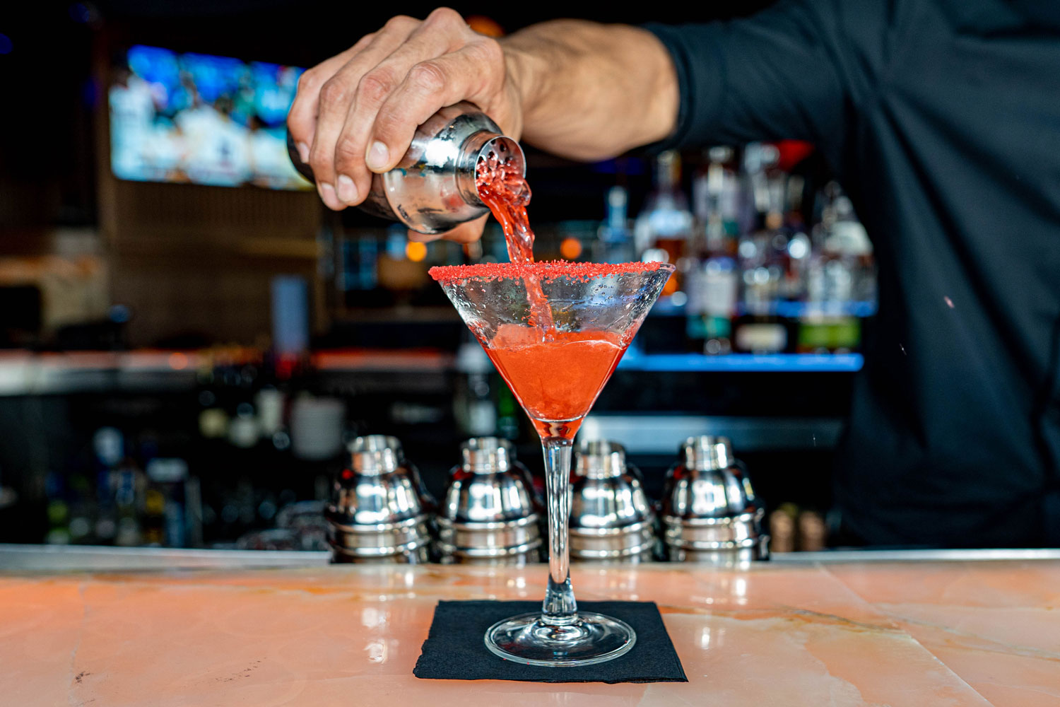 A bartender crafting a signature martini, showcasing the vibrant nightlife atmosphere.