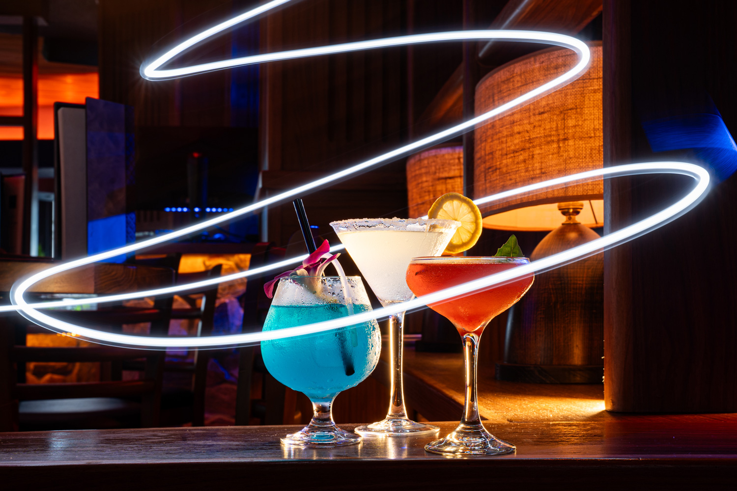Signature Blue Martini cocktails on the bar with colorful lighting and creative garnish